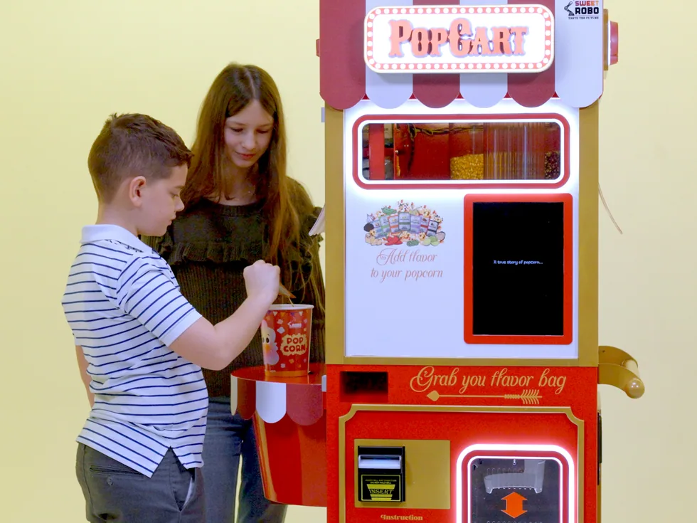 Kids getting fresh popcorn from the Sweet Robo PopCart popcorn machine